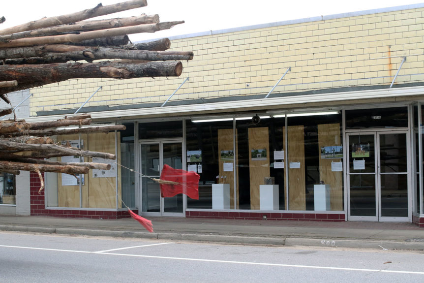 Logging truck wizzes by storefront in quiet downtown rural community
