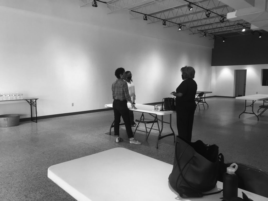black and white photograph of small (three) African American women masked, standing and talking.